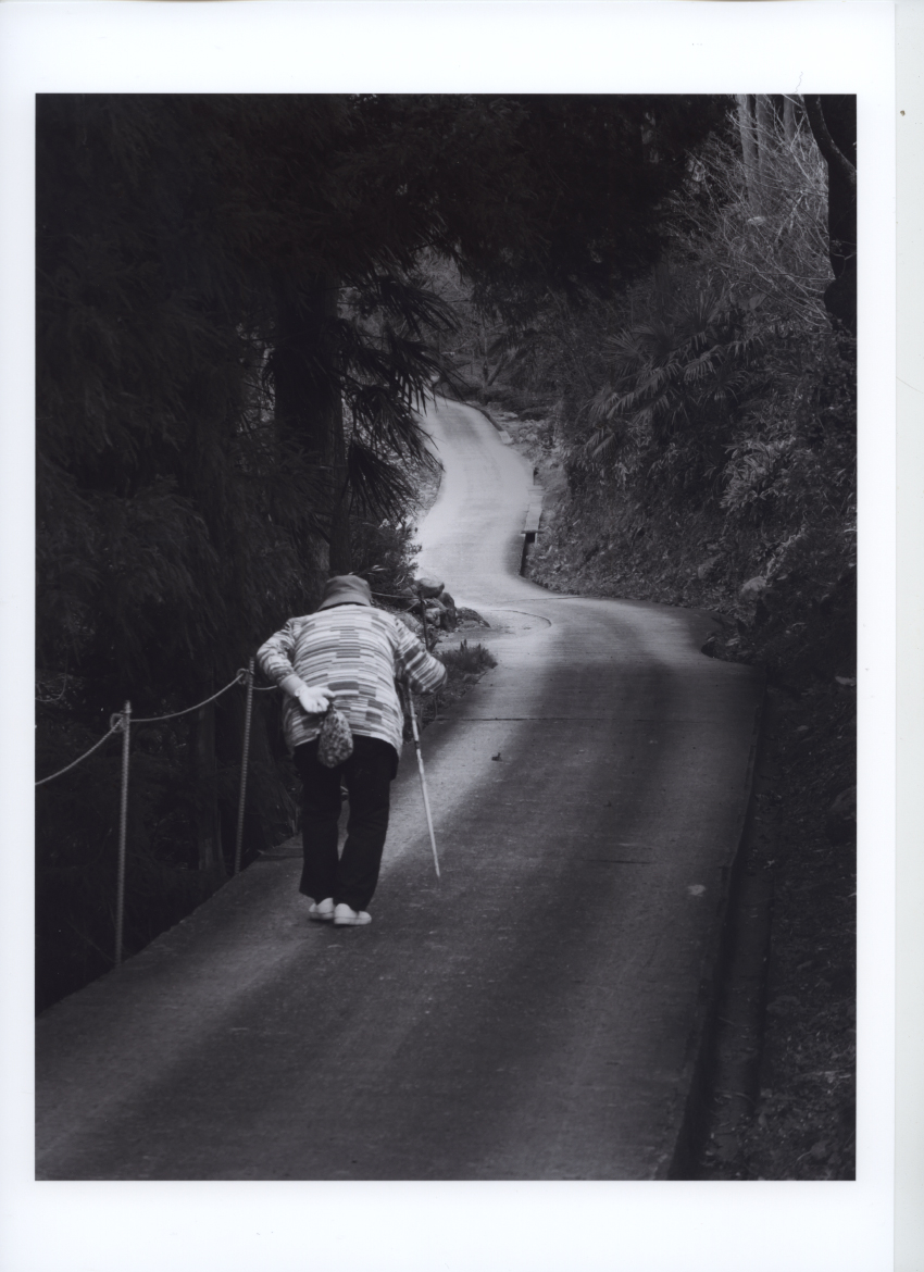 一本道を下る老女